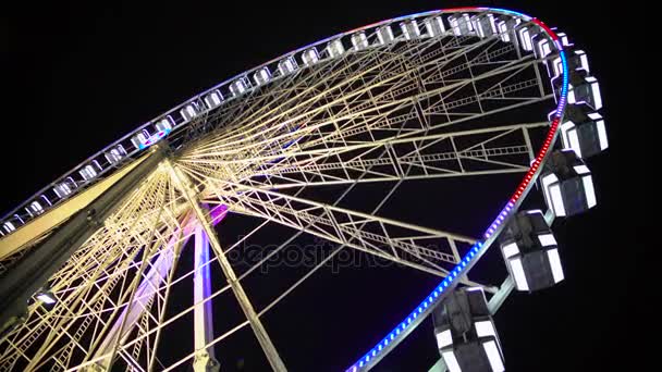 Riesenrad im Freizeitpark, bunt beleuchtete Konstruktion bewegt sich langsam — Stockvideo