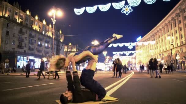 KYIV, UCRANIA - CIRCA MARZO 2016: Actuación callejera en el centro de la ciudad. Pareja deportiva sonriente practicando acro yoga posa en la calle, hobby extremo — Vídeos de Stock