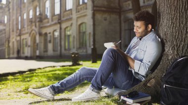 Not defterinde, ilham almak ağacın altında oturup karışık ırk genç adam