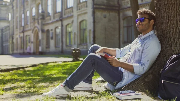 Hombre multiracial sentado bajo el árbol con gafas de sol, estado de ánimo positivo, energía —  Fotos de Stock