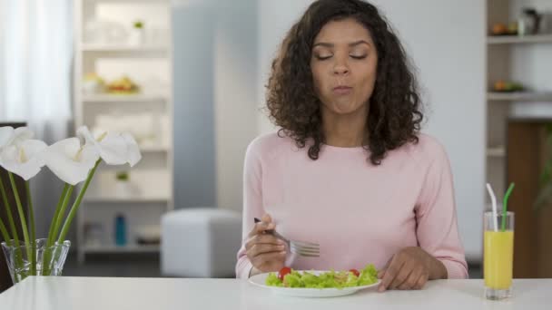 Молодая женщина смешанной расы ест салат за столом, здравоохранение и здоровое питание — стоковое видео