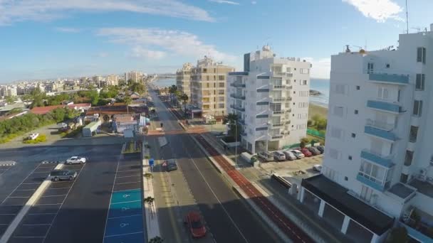 Vista aérea ao longo da rua com casas, estacionamento e cafés na cidade de Larnaca — Vídeo de Stock