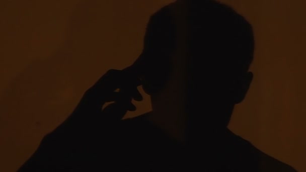 Dolorous male silhouette talking on cellphone, upset man regrets losing his job