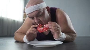 Adam yerde yatıyor ve çörek, bağımlılığı çiğneme spor giyim kilolu