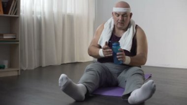 Erkek spor giyim zor egzersiz yaptıktan sonra mat ve içme suyu üzerinde oturan şişman