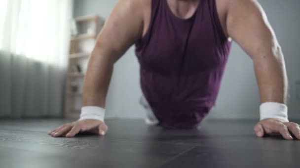 Sudando regordete hombre en su 50s haciendo flexiones con gran esfuerzo, entrenamiento en casa — Vídeo de stock