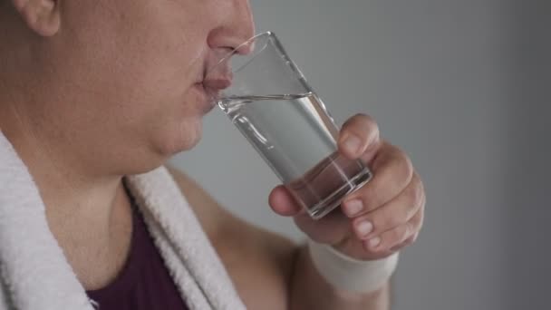 Nahaufnahme eines pummeligen Mannes, der frisches Wasser aus dem Glas trinkt und lächelt — Stockvideo