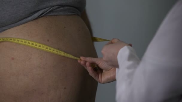 Médica que mede a cintura do seu paciente gordo do sexo masculino, problemas de peso — Vídeo de Stock