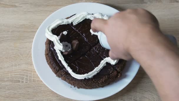 Мужчина украшает торт со взбитыми сливками и вишней сверху, риск сахарного диабета — стоковое видео
