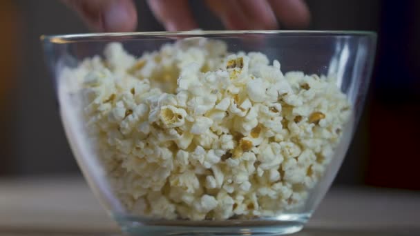Männerhände, die Popcorn aus der Glasschüssel holen, Fernsehsendungen gucken und essen — Stockvideo
