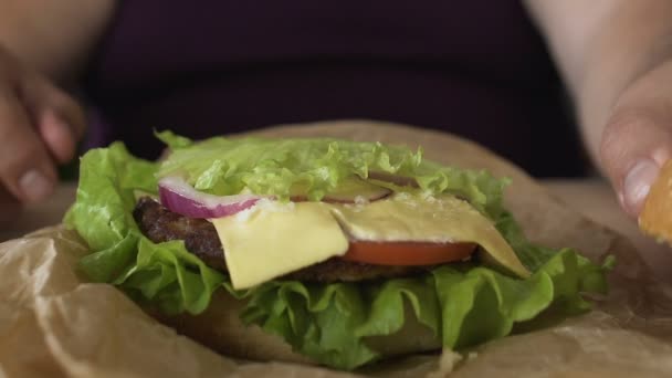 Hombre cocinando cuidadosamente sándwich de hamburguesa con queso, adicción a la comida chatarra, de cerca — Vídeo de stock