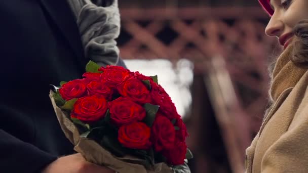Чоловік представляє дівчину з купою квітів, ніжні обійми закоханих — стокове відео