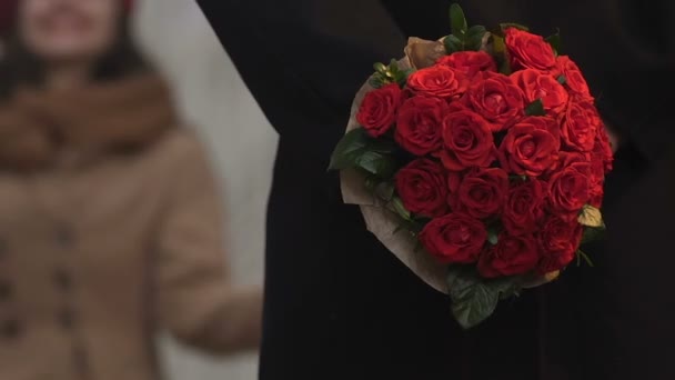 Брюнетка опаздывает на свидание, мужчина ждет с цветами, дарит букет женщине — стоковое видео