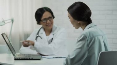 Test sonuçlarını dizüstü bilgisayarda gösterilen hekim bildiren hastayı iyi haber,