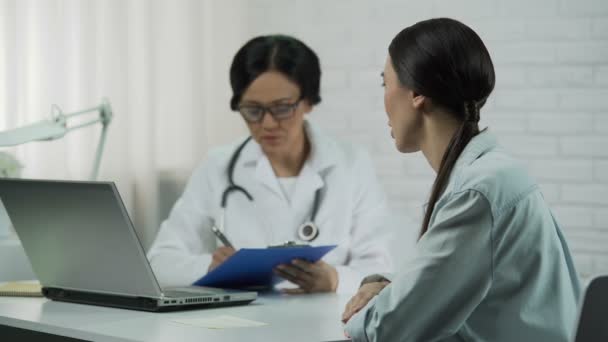 Médico escuchar a paciente en el consultorio, mujer se queja de la enfermedad, dolor de cabeza — Vídeo de stock