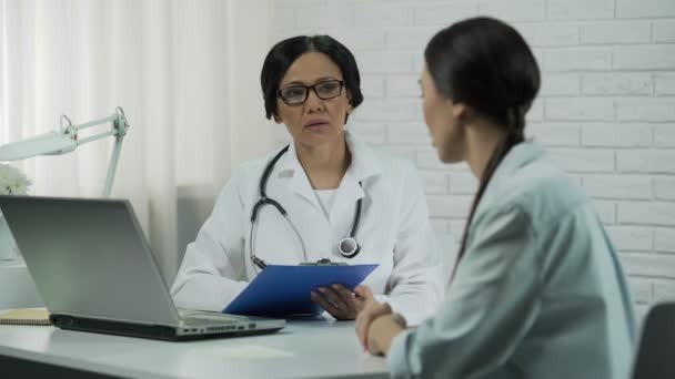 Пацієнт під час консультації лікаря, терапевт, який вислуховує та записує симптоми — стокове відео
