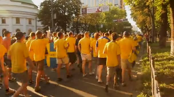 Kyjev, Ukrajina - cca červen 2012: Fotbaloví fanoušci ve městě. Průvod fanoušků rychle pohybuje směrem ke stadionu na podporu jejich národního týmu — Stock video