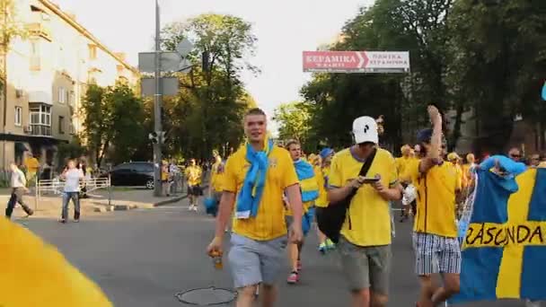 КИЕВ, Украина - CIRCA JUNE 2012: Футбольные болельщики в городе. Мужчины с цветными лицами, одетые в футбольные атрибуты, идут на футбольные соревнования — стоковое видео