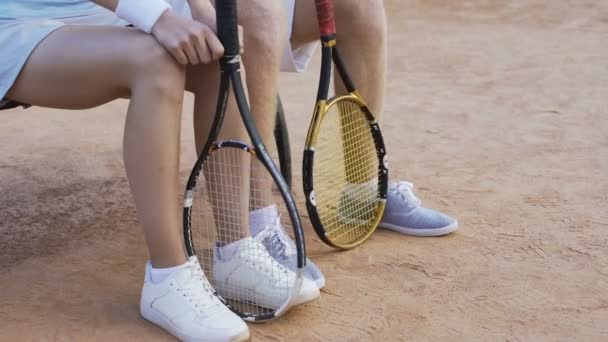 Nerwowy płci męskiej i żeńskiej tenisista czekam na mecz na ławce, szczelnie-do góry nogami — Wideo stockowe