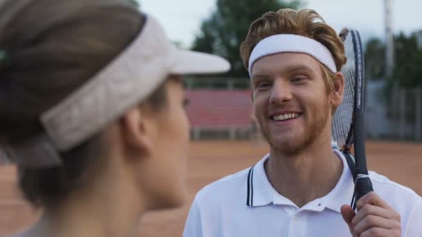 Feminino flertando com jogador de tênis ruivo na corte, homem sorrindo para a menina — Vídeo de Stock