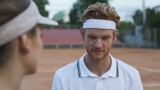 재미 있는 빨간 머리 남자 윙크와 테니스 코트에서 아름 다운 여성을 유혹 — 비디오