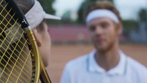 Hübsche Frau mit Schläger redet mit Mann im Tennisclub, Paar flirtet — Stockvideo