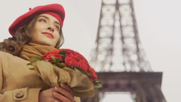 Boldog szép lány megcsodálta csokor vörös rózsa, háttérben az Eiffel-torony — Stock videók