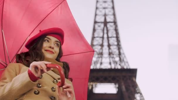 Счастливая леди, стоящая под зонтиком и улыбающаяся прохожим, ждет своего друга — стоковое видео