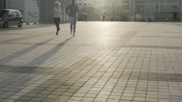 Paar erwachsene Freunde joggen im Stadtgebiet und nähern sich langsam der Kamera — Stockvideo