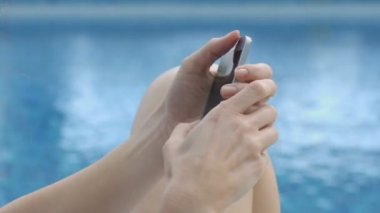 Suyun kenarında oturan ve mesaj smartphone, online yazışma yazma kadın