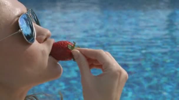 Atractiva mujer seductora comiendo fresa dulce cerca de la piscina, verano flirtear — Vídeo de stock