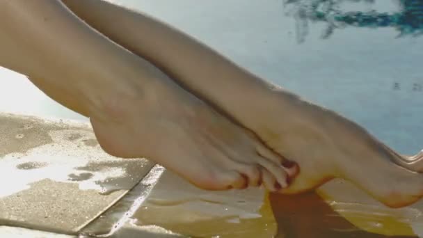 Svůdná žena těší hedvábnou kůži na nohách po depilaci, sedí u bazénu — Stock video