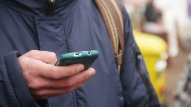 Smartphone cep telefonu ile hareket eden app zamanlama denetimi, toplu taşıma için bekleyen adam
