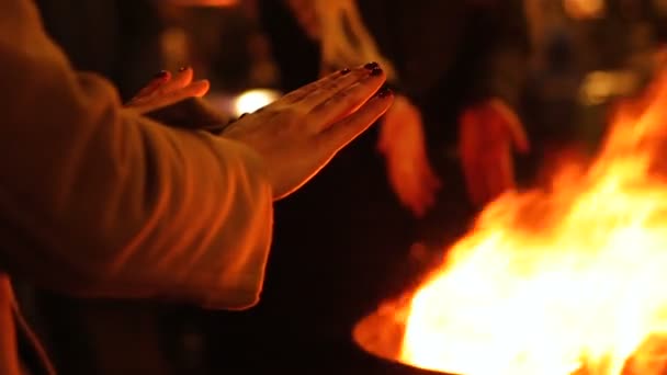 Люди греют руки у костра на уличном фестивале, празднуют зимние праздники — стоковое видео