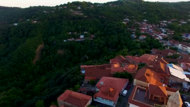 Drone voando sobre as colinas verdes e belos edifícios em Sighnaghi ao pôr do sol — Vídeo de Stock