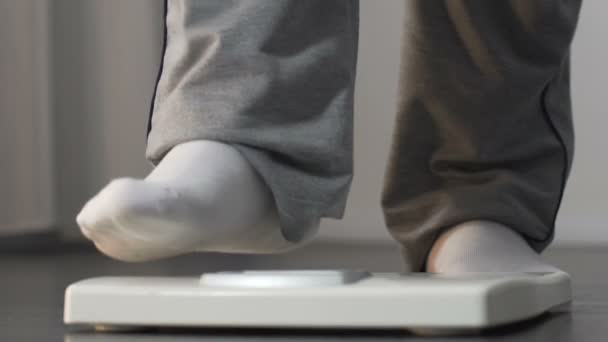 Játékos túlsúlyos ember rálép a skála, és emeli a lábát, fogyás — Stock videók