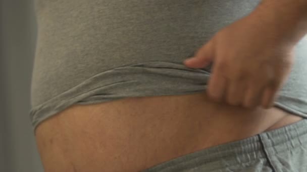Legrační obézní člověk dotýká jeho pivo tuk před zrcadlem, vyšší hmotnost — Stock video