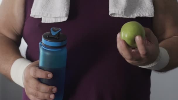 Vista del hombre gordo comiendo manzana verde después de un duro entrenamiento cardiovascular, dieta y salud — Vídeo de stock