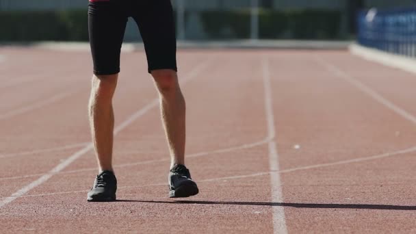 Deportista calentando los músculos de las piernas en el estadio para una mejor circulación sanguínea — Vídeos de Stock