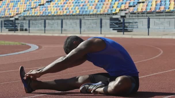 Atleta hispano calentando su espalda, haciendo ejercicios de flexibilidad en pista de carreras — Vídeos de Stock