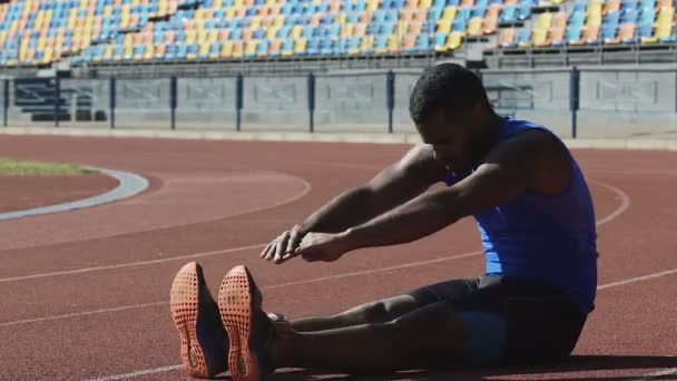 Spaanse atleet voltooiing van de reeks van dagelijkse oefeningen zittend op de atletiekbaan — Stockvideo