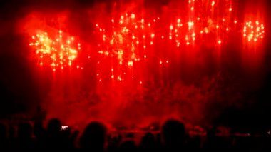 Kalabalık insan gece gökyüzünde havai fişek parlak su sıçramalarına hayranlıkla izliyor