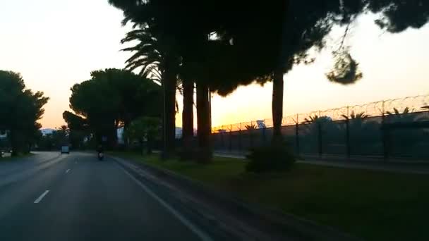 Blick aus dem Autofenster auf die rote Sonnenscheibe hinter dem Flughafen, Anreise mit dem Auto — Stockvideo