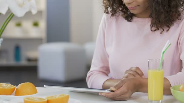 Online winkelen, vrij gemengd ras vrouw scrollen op de tablet bij de keuken — Stockvideo