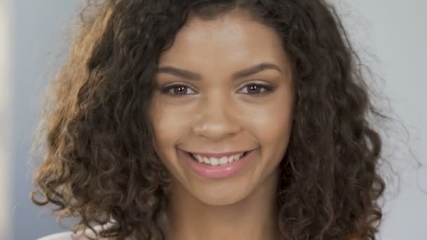 Retrato de mujer alegre birracial aplicando mitades de naranja a los ojos, optimismo — Vídeos de Stock