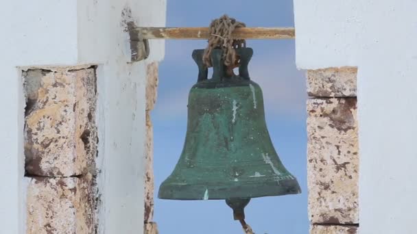 Старый ржавый колокол висит в белой арке на голубом фоне, церковь в Греции — стоковое видео