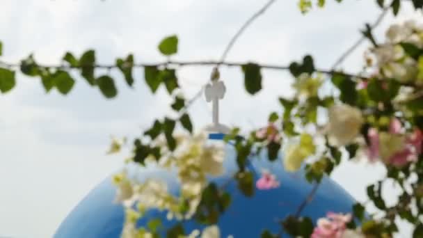 Cruz de pie en la cúpula de la iglesia azul, ramas floreciendo en frente, turismo de Grecia — Vídeos de Stock