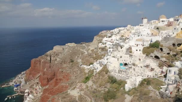 Case bianche che si trovano sulla cima della montagna su Santorini, baia in fondo alla scogliera rossa — Video Stock