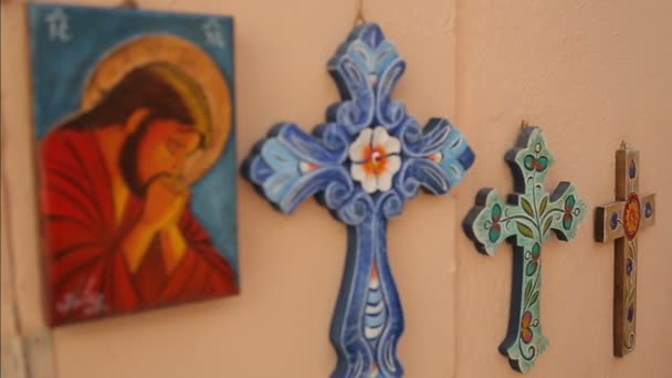 SANTORINI, GRECIA - CIRCA JULIO 2014: Turismo en la isla. Jesús pintando colgando en la pared junto con cruces de colores, fe y religión — Vídeo de stock