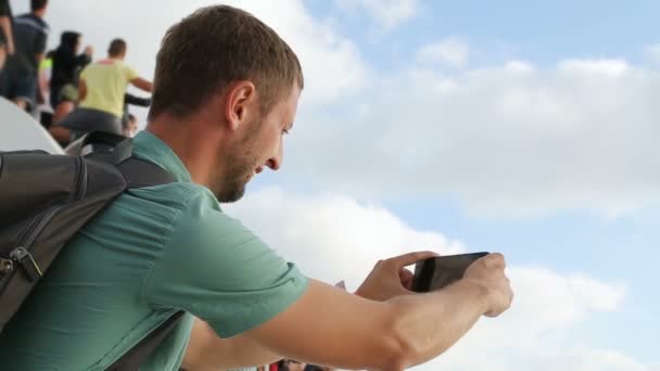 Tipo sosteniendo su teléfono celular en frente, grabando escena interesante, festival — Vídeo de stock